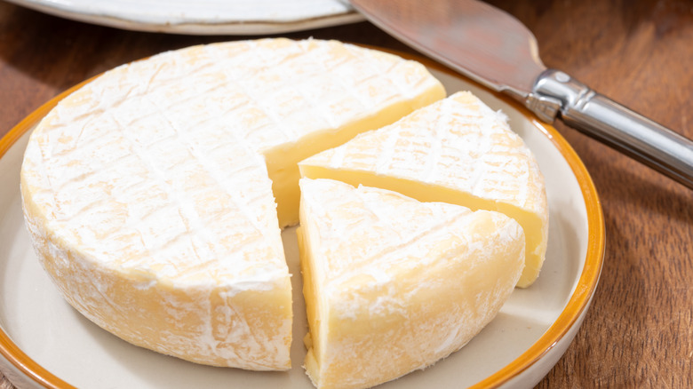A plate of Brie cheese on a plate with a knife