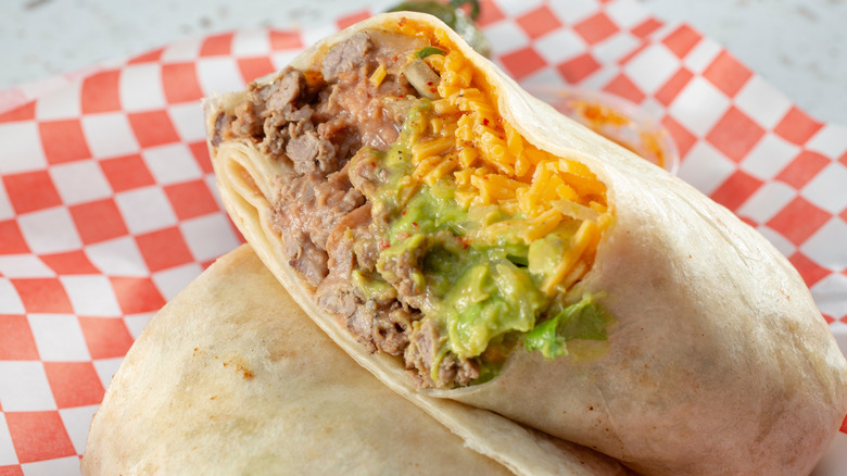 A carne asada burrito, sliced open to expose the ingredients inside