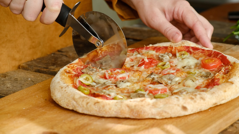 A person slicing a pizza