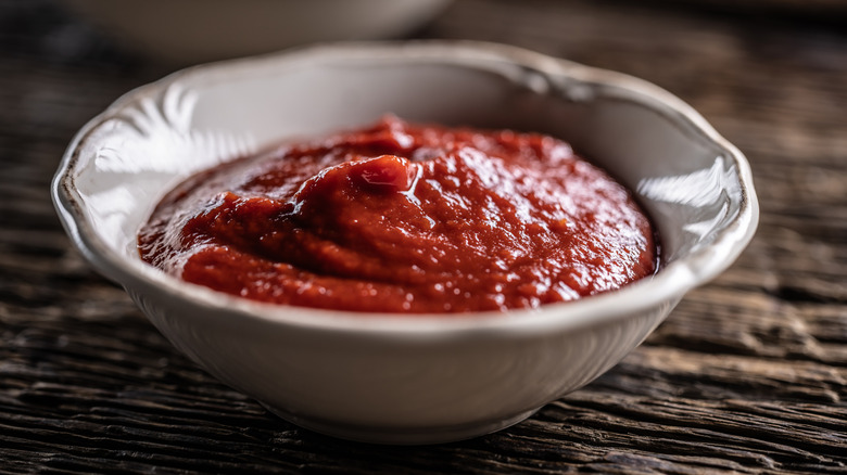 A white bowl of tomato sauce or paste