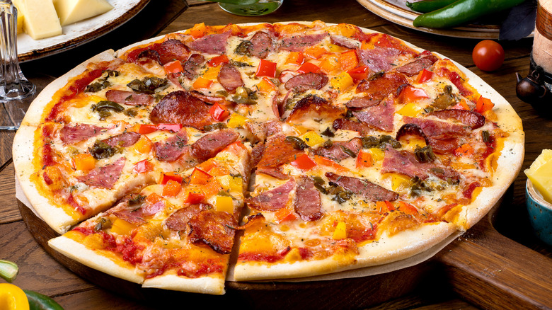 A pizza with many toppings sits on a wooden table