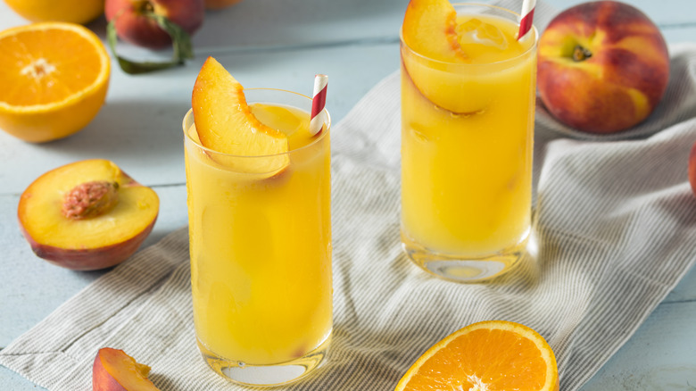 Two Fuzzy Navel cocktails on tabletop with sliced fruit