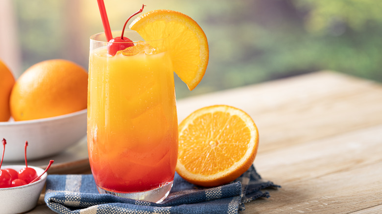 Tequila Sunrise cocktail posed on tabletob with sliced oranges