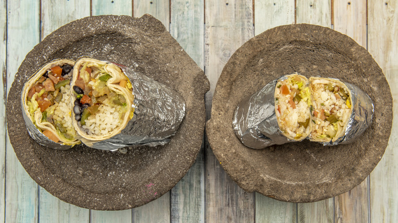 Two stuffed burritos, cut in half and arranged on plates