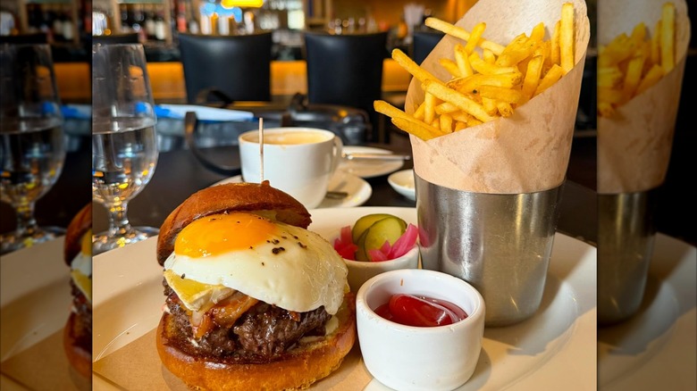 A burger topped with a fried egg and fries, served at Wayfare Tavern