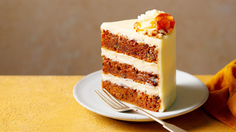 A slice of carrot cake on a white plate with a fork