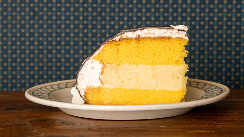 A slice of Boston cream pie on a rustic plate with a decorative blue pattern around the edges