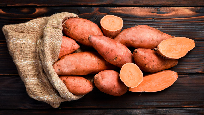 A bag full of sweet potatoes on a wooden table