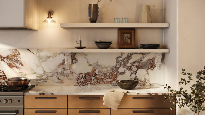 A kitchen countertop and prominent backsplash made of marble with reddish-brown veins