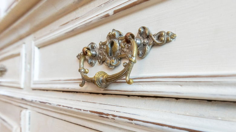 Closeup of an ornate, gilded drawer handle