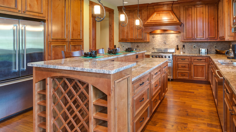 An elegant wooden kitchen with built-in wine racks at the end of the island