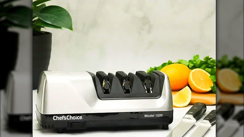 chef's choice knife sharpener with two knives on the side and a whole orange and a sliced orange in the background