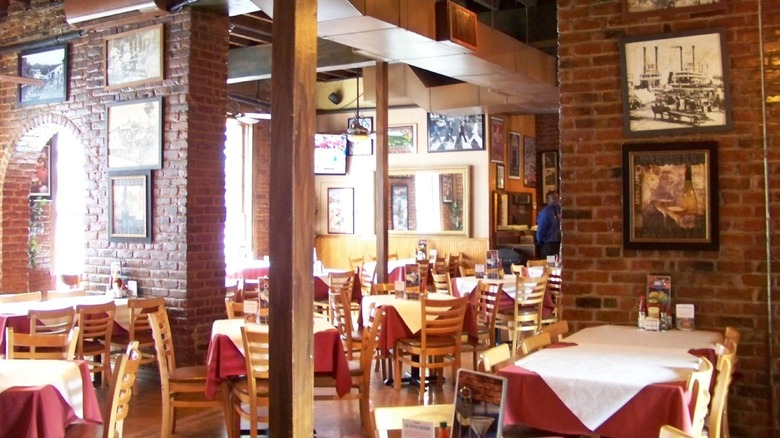 Brick interior of Oceana Grill with four-seater tables topped with a red tablecloth and a white one on top.