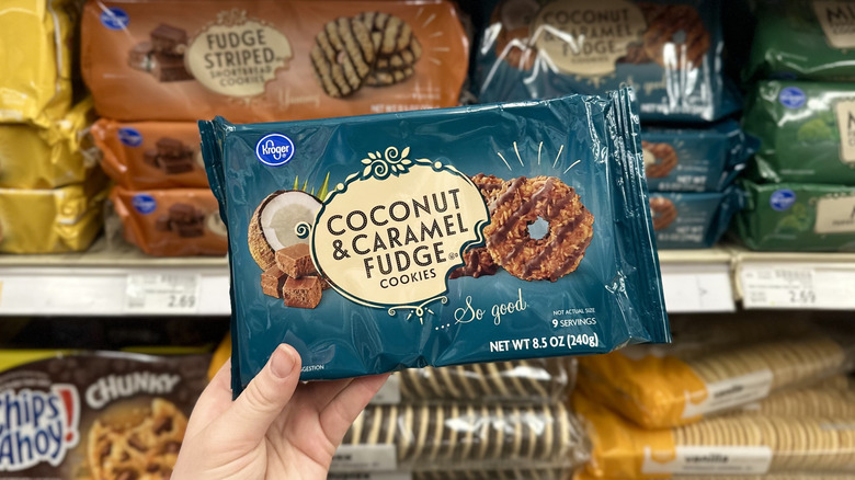A hand holding a package of Kroger Coconut & Caramel Fudge cookies