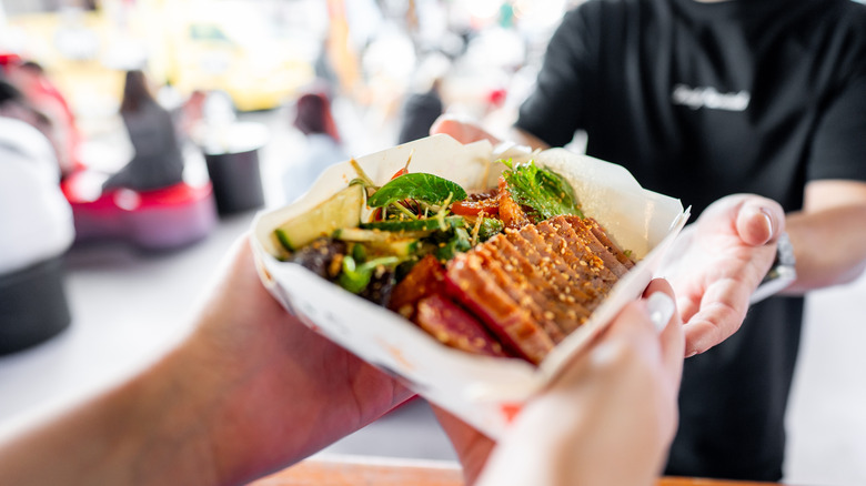 A server hands someone a portion of food at a food court