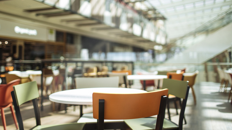 An empty food court in a mall, with chairs in the foreground