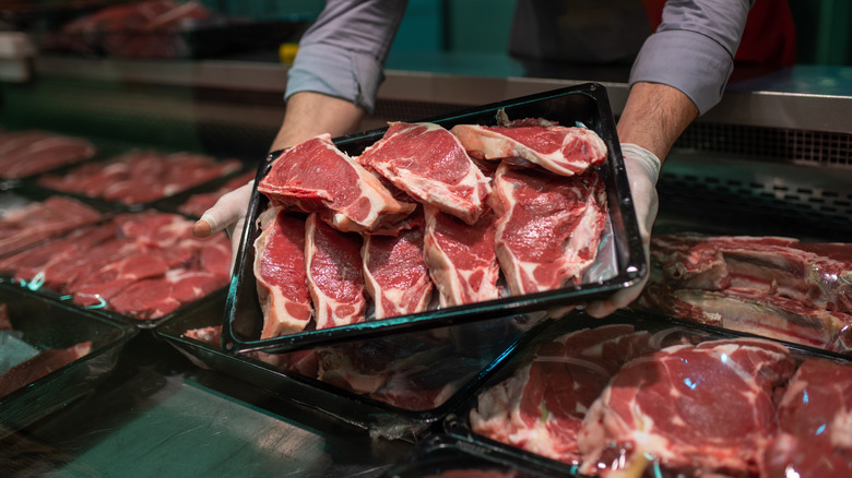 Close-up of a butcher's hands holding a package of meat