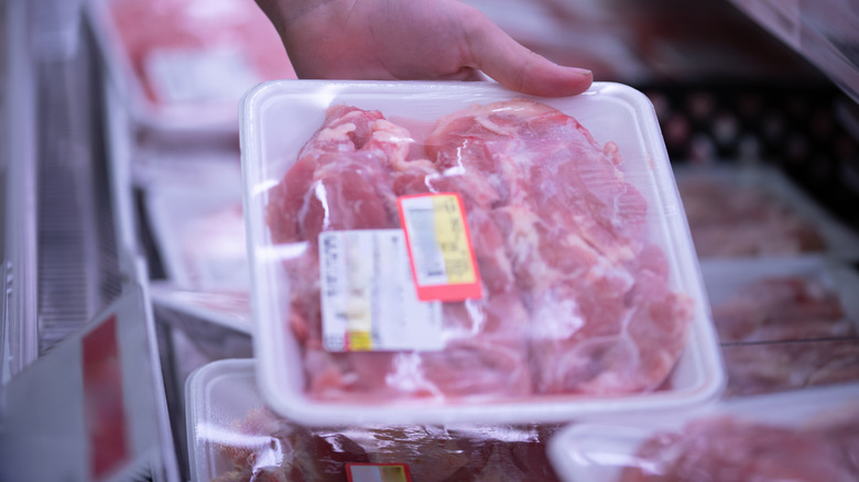 A person holds a pack of reduced meat