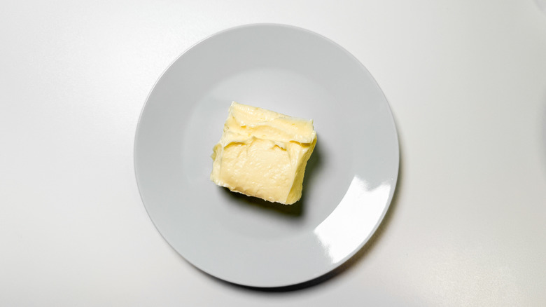 A single pat of butter sits on a white dish
