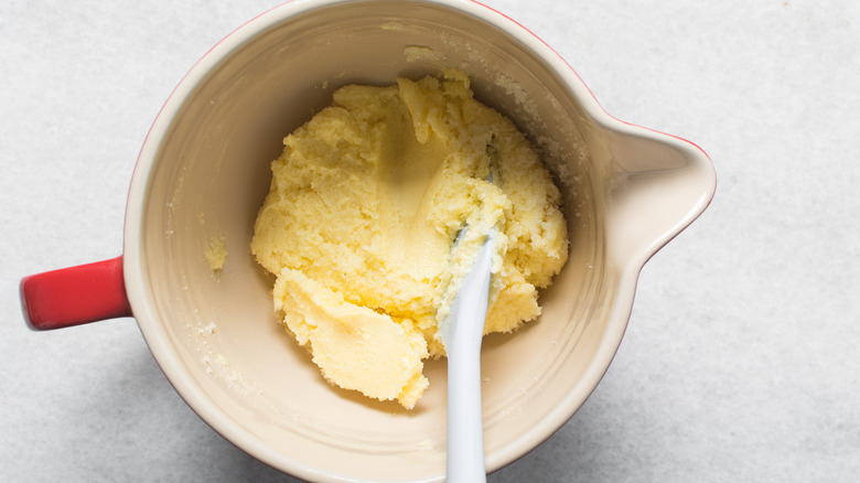 Top view of butter and sugar being creamed together with a spatula in a big bowl
