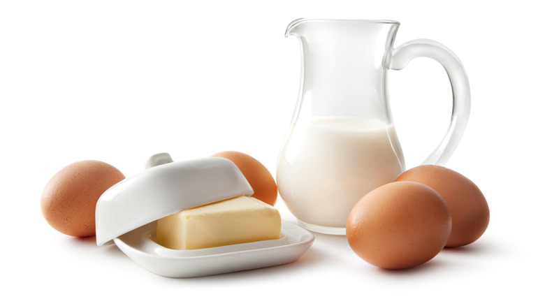 A pitcher of milk, four eggs, and a container of butter