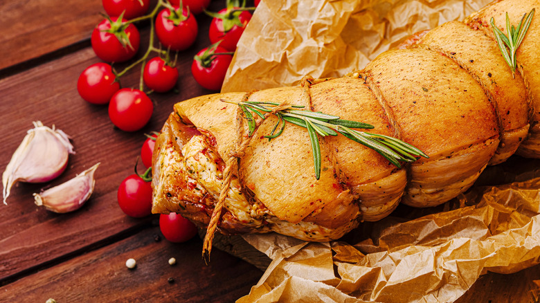 A rolled meat dish sits on crumpled parchment paper