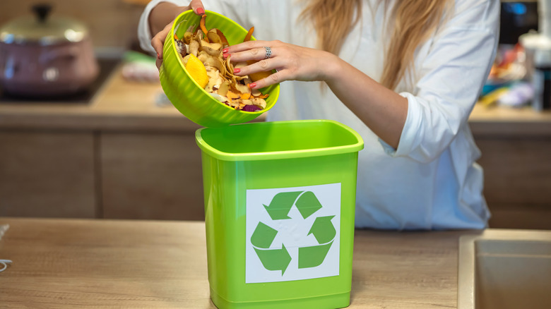 woman putting food in compost bin