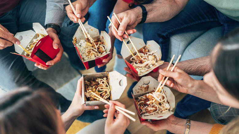 people eating out of takeout containers