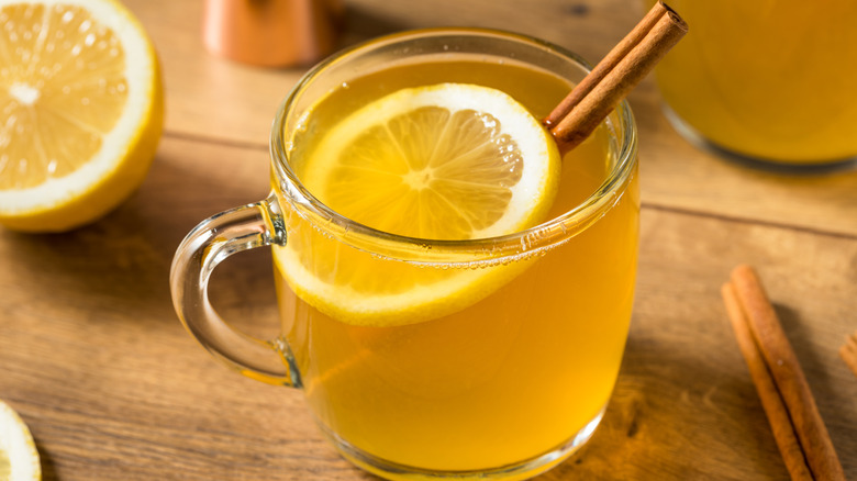 A hot toddy with a slice of lemon and cinnamon inside the glass