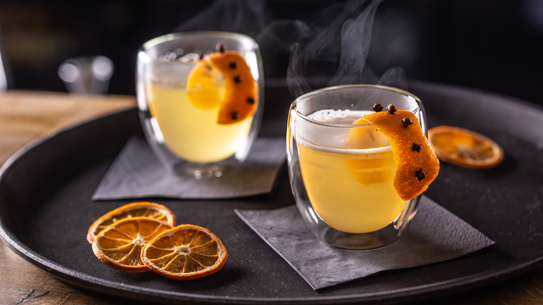 Two hot toddies with orange peels on a plate