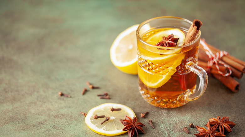 A small glass of hot toddy with whole spices and lemon