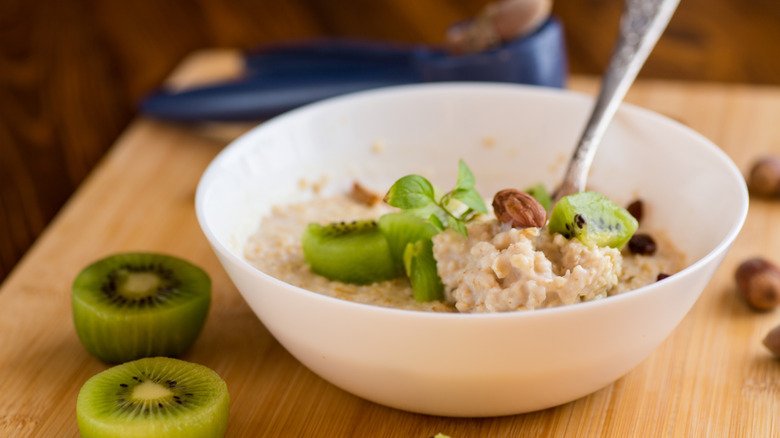 A bowl of oatmeal, topped with sliced kiwi