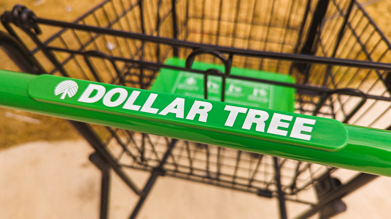 The green handle of a Dollar Tree shopping cart
