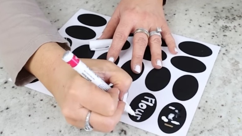 A woman writing on chalkboard stickers with a chalk marker
