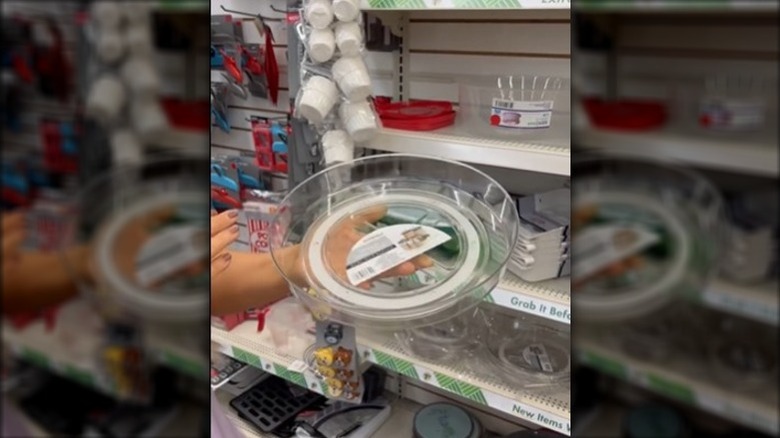 A person holding a clear acrylic rotating kitchen turntable