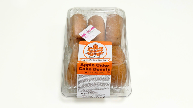 A container of apple cider cake donuts against a white background