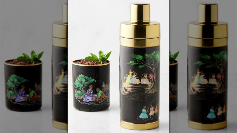 A brass-plated cocktail shaker decorated with pastoral scenes featuring black people enjoying nature