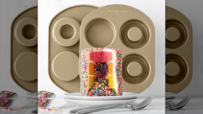 Two cake pans with mostly raised centers, with a rainbow sprinkles-stuffed rainbow cake in the middle