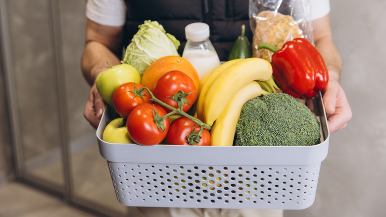 A shopper holding a basket of fresh fruits and vegetables