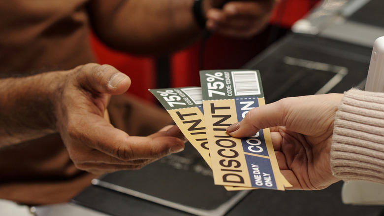 A shopper handing the cashier two coupons