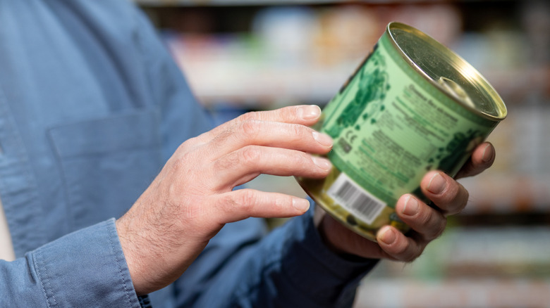 A shopper checking the label on a canned food item