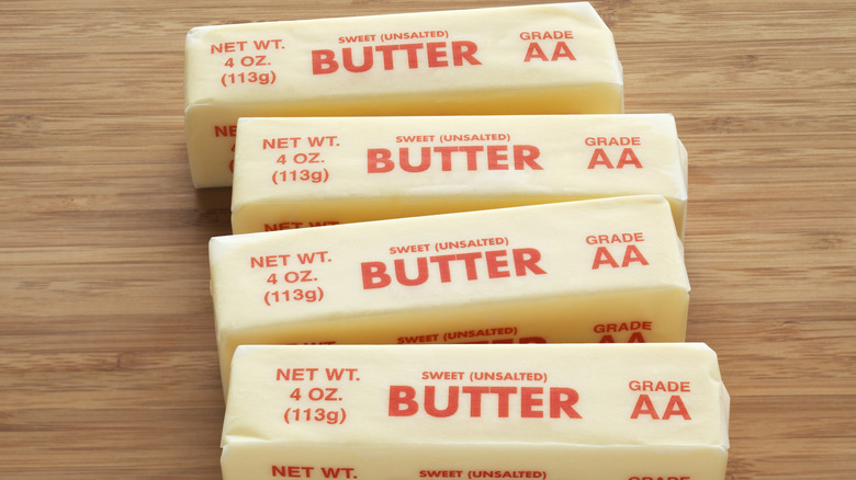 Four sticks of room temperature unsalted butter on a wood surface