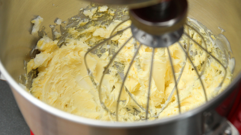 Pale yellow butter being whipped in a metal stand mixer