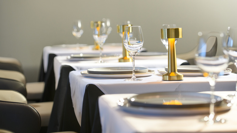 Set tables in a fashionable restaurant, with wine glasses, plates, and table lamps