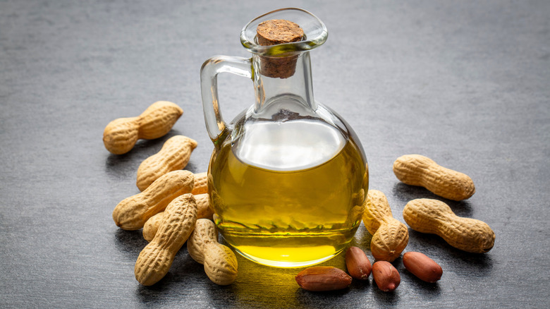 A bottle of peanut oil, with peanuts around it