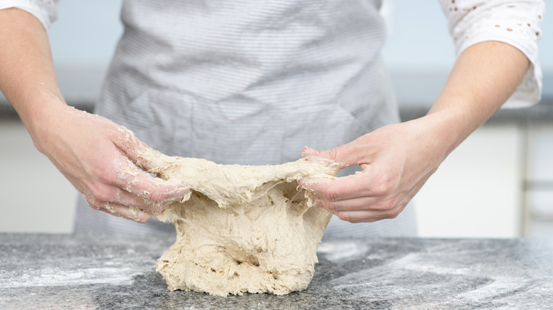 A baker uses the slap and fold technique to knead bread dough