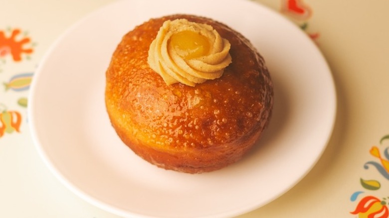 A glazed donut with rum baba cream and apricot marmalade on top