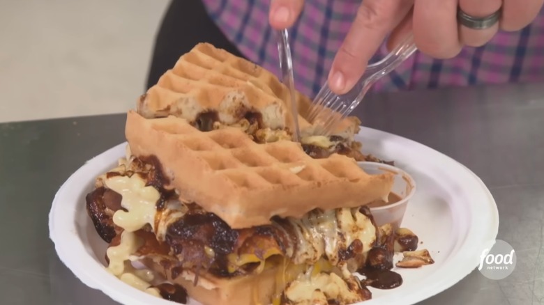 Guy Fieri uses a knife and fork to cut into the Confused Cousin Chicken Sandwich at Waffles and Whatnot