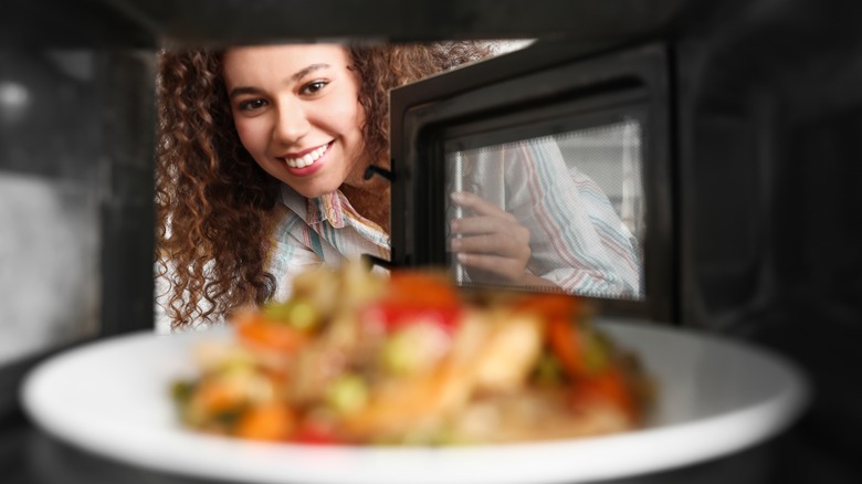 Woman putting plate in microwave