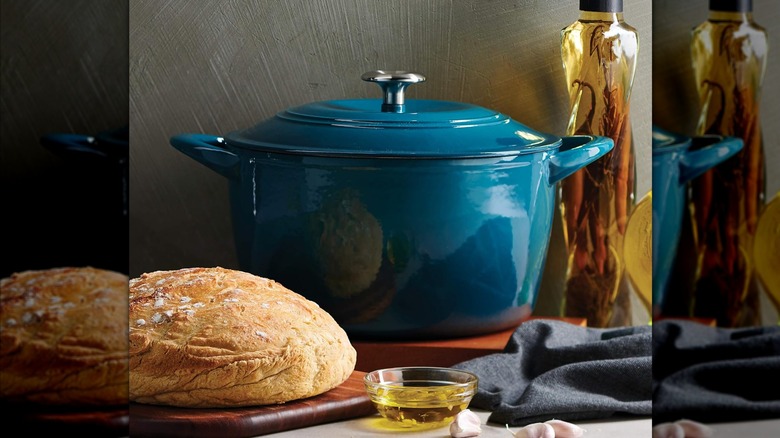 A blue Tramontina Dutch oven  with bread and a bottle of infused olive oil
